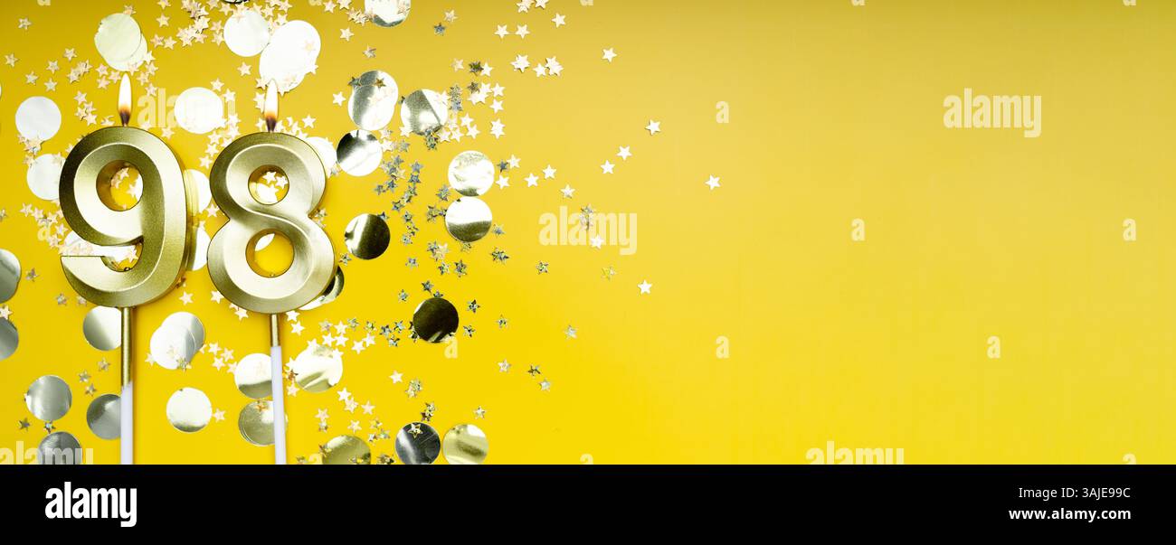 Quatre-vingt-dix-huit ans. Bougie de célébration numéro 98 dorée. Fond festif jaune. Concept de célébrer un anniversaire ou un anniversaire. Bannière. Banque D'Images