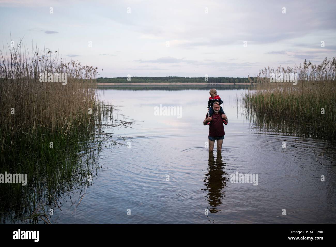 Grand-père portant petit-fils sur les épaules tout en marchant dans le lac Banque D'Images