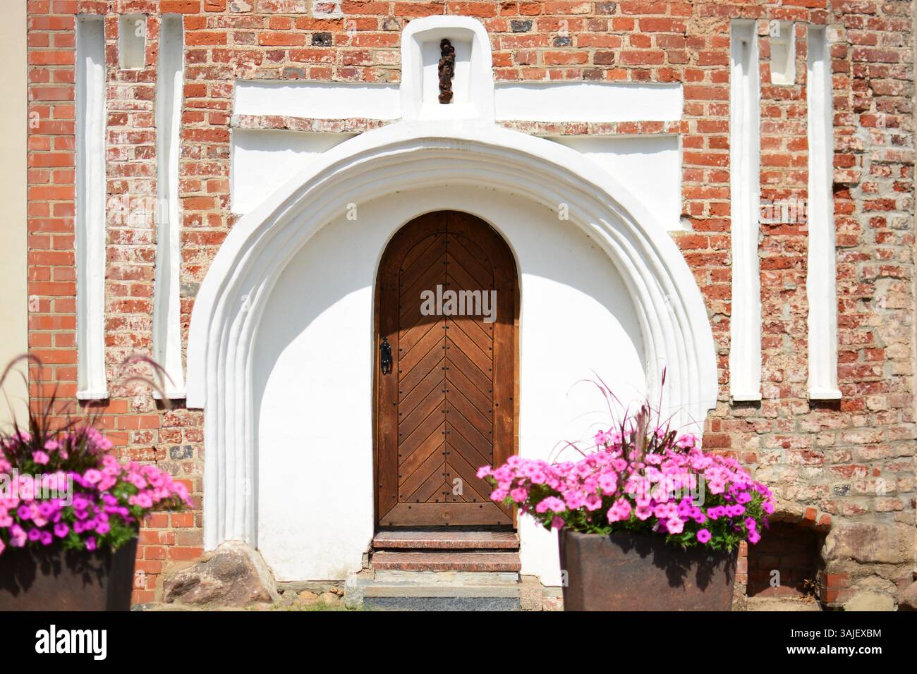 Vieilles portes brunes en bois vintage. Fragment de mur ornemental et escaliers. Entrée de la vieille église décorée de pots de fleurs. Banque D'Images