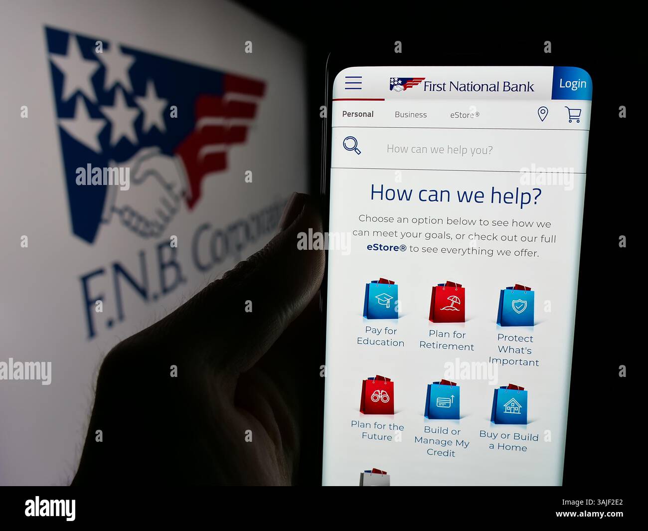 Dans cette illustration photo, une personne tient un téléphone portable avec la page Web de la société américaine FNB Corporation (First National Bank) sur l'écran avec logo. Banque D'Images