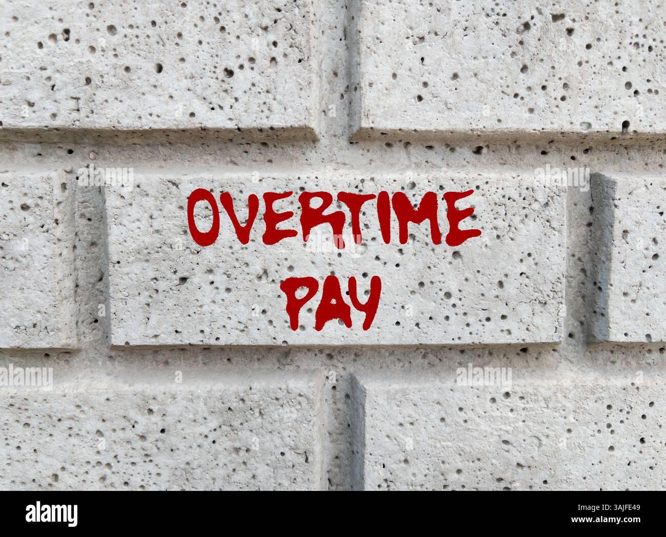 Message de paie d'heures supplémentaires écrit sur le mur de pierre grise. Symbole conceptuel de rémunération des heures supplémentaires. Copier l'espace. Banque D'Images