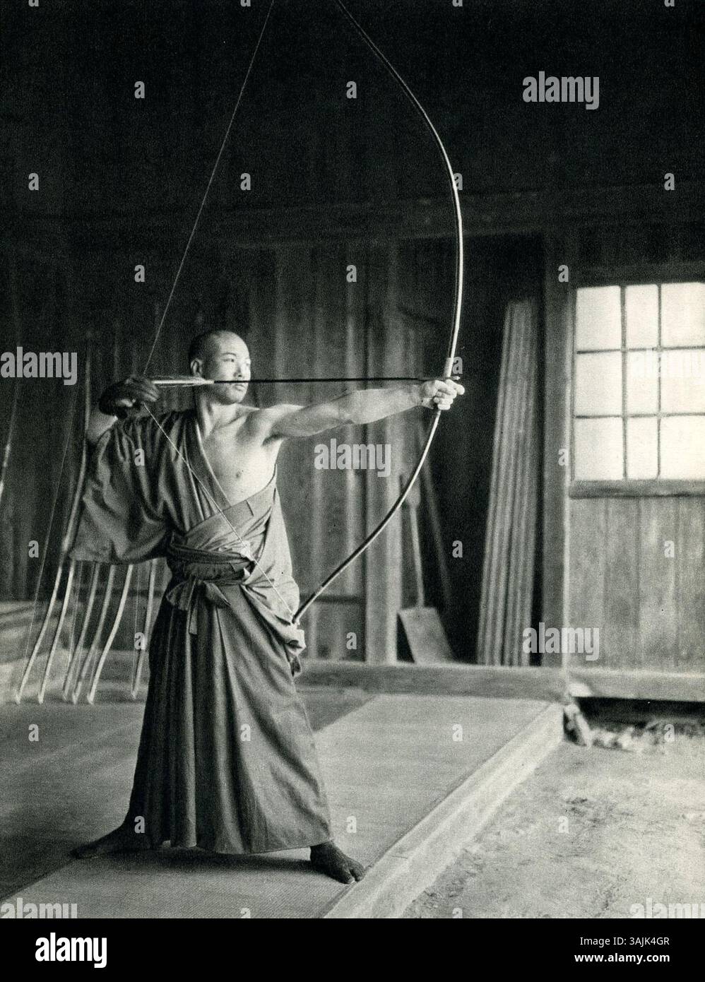 Un archer japonais, un Kyudoka, dessine un arc-en-long Daikyu. Le Daikyu est un arc traditionnel asymétrique, utilisé par les archers experts au Japon depuis des siècles, en particulier dans l'art du Kyudo. Banque D'Images