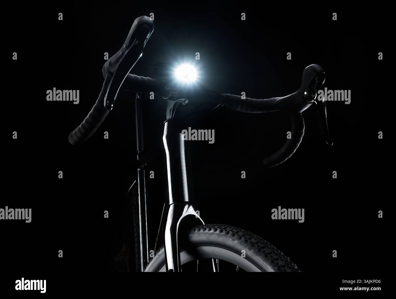 Vélo de gravier noir avec éclairage, phare blanc, sécurité cycliste sur fond sombre. Banque D'Images