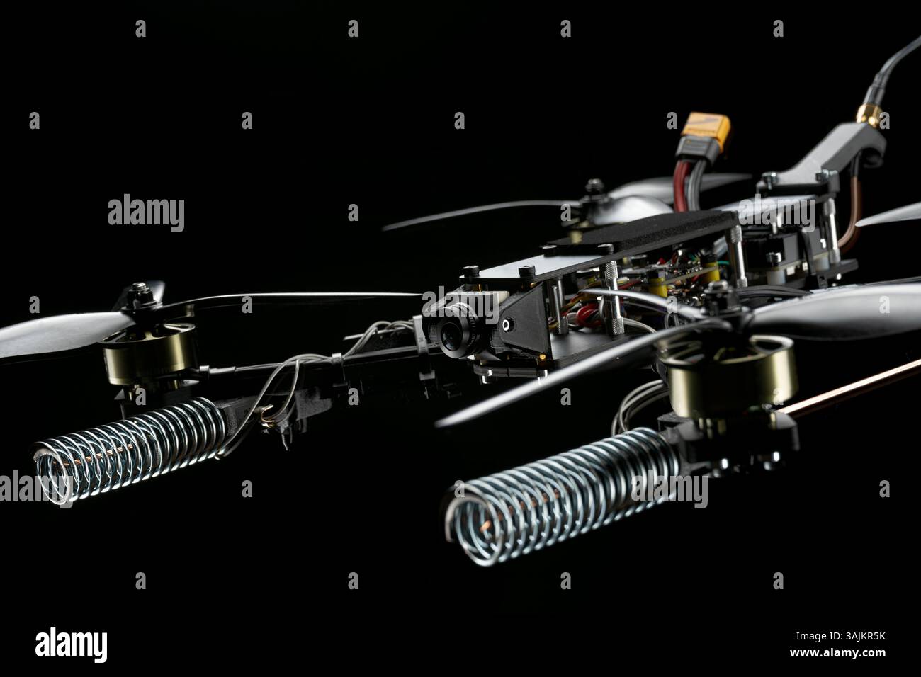 Vue rapprochée détaillée d'un drone de course compact avec ses hélices, ses moteurs, sa caméra et ses composants électroniques complexes sur fond sombre. Banque D'Images