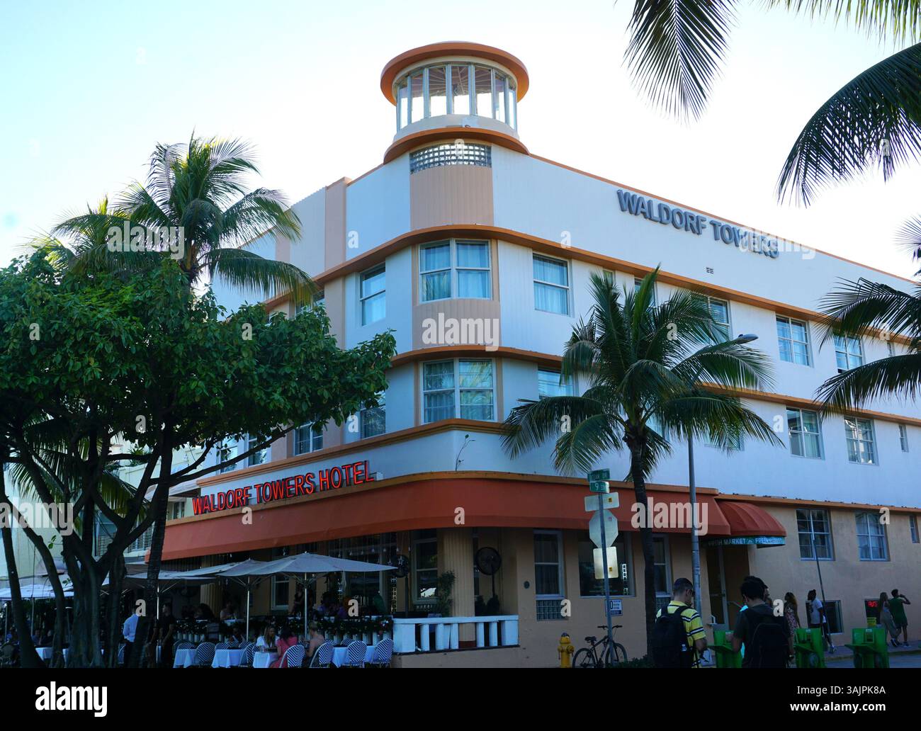 Les touristes s'assoient dans un bar en face de l'historique Waldorf Towers Hotel dans le quartier Art déco de Miami, ou quartier architectural de Miami Beach. Banque D'Images