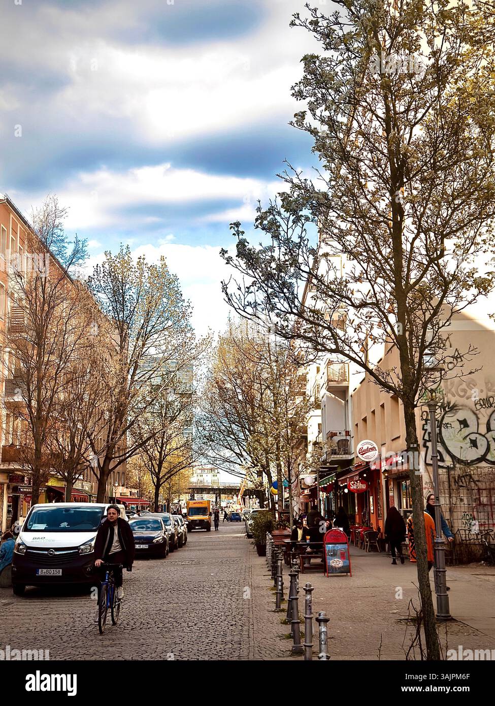 Une scène de rue berlinoise animée avec des habitants qui font du vélo et se promènent devant des cafés et des boutiques Banque D'Images