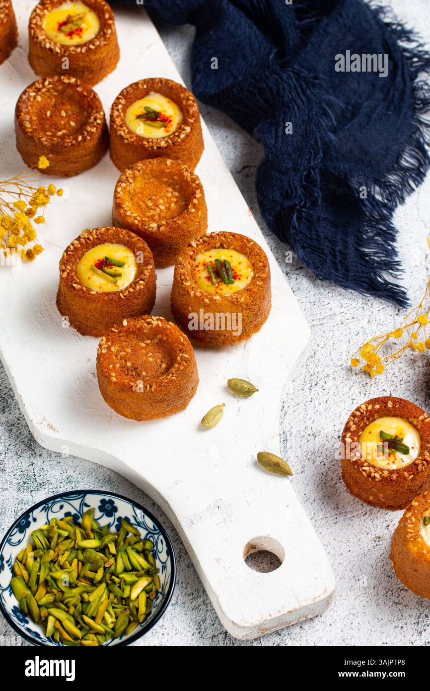 Mini gâteaux Basbousa avec sauce safran et pistache – dessert arabe stylisé sur fond blanc Banque D'Images