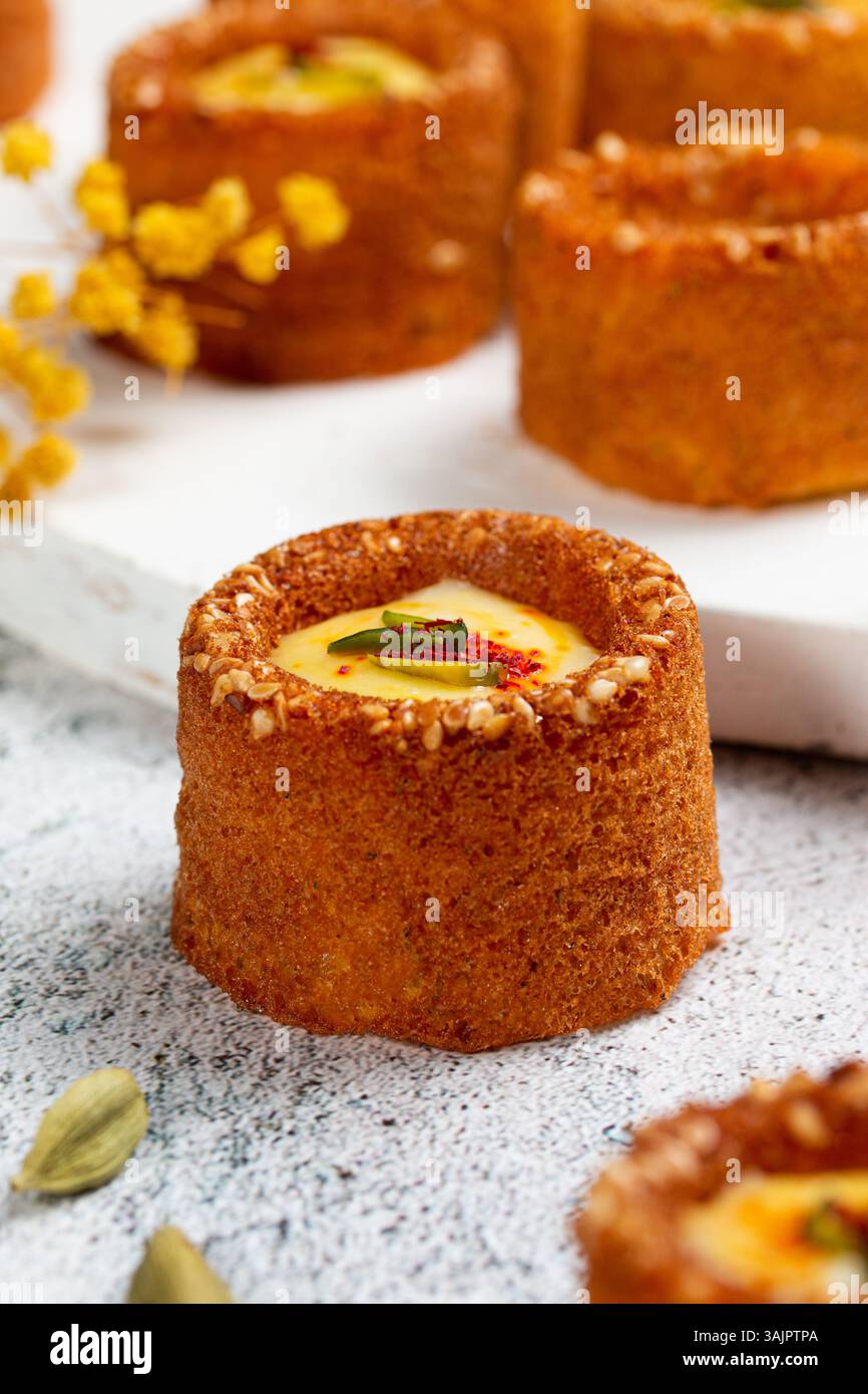 Mini gâteaux Basbousa avec sauce safran et pistache – dessert arabe stylisé sur fond blanc Banque D'Images