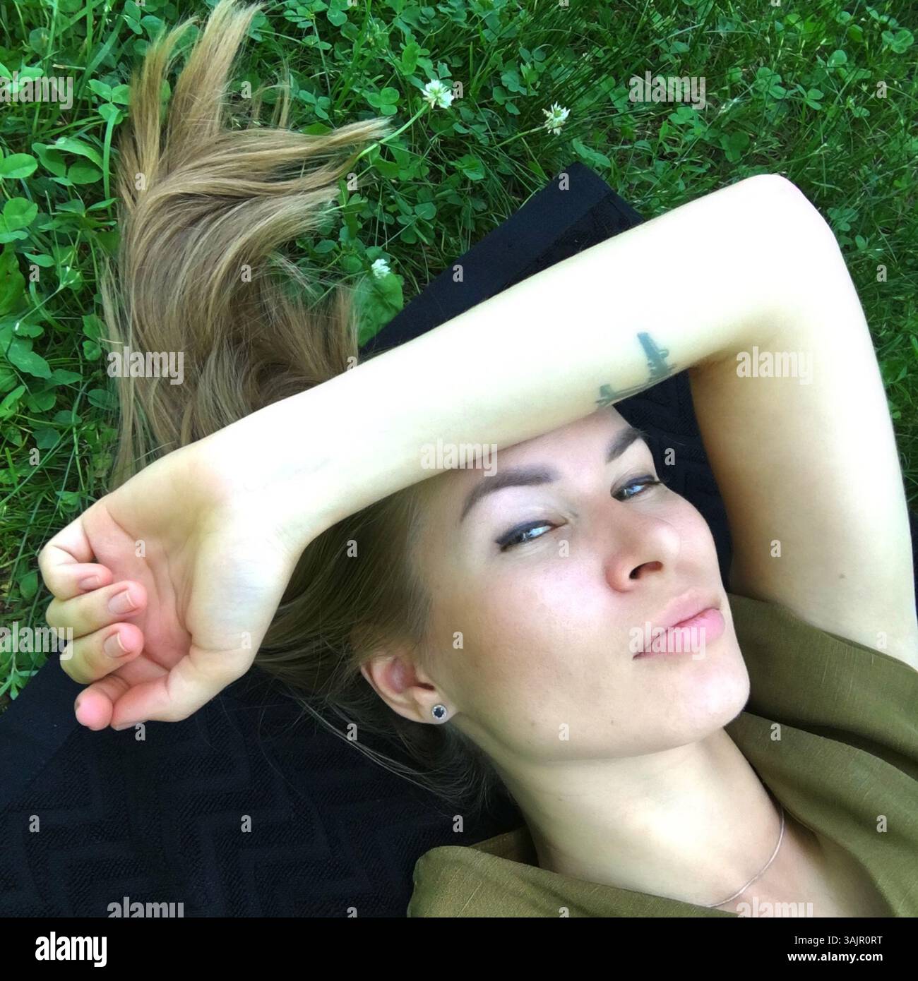 Jeune femme allongée sur l'herbe avec ses mains derrière la tête. Banque D'Images