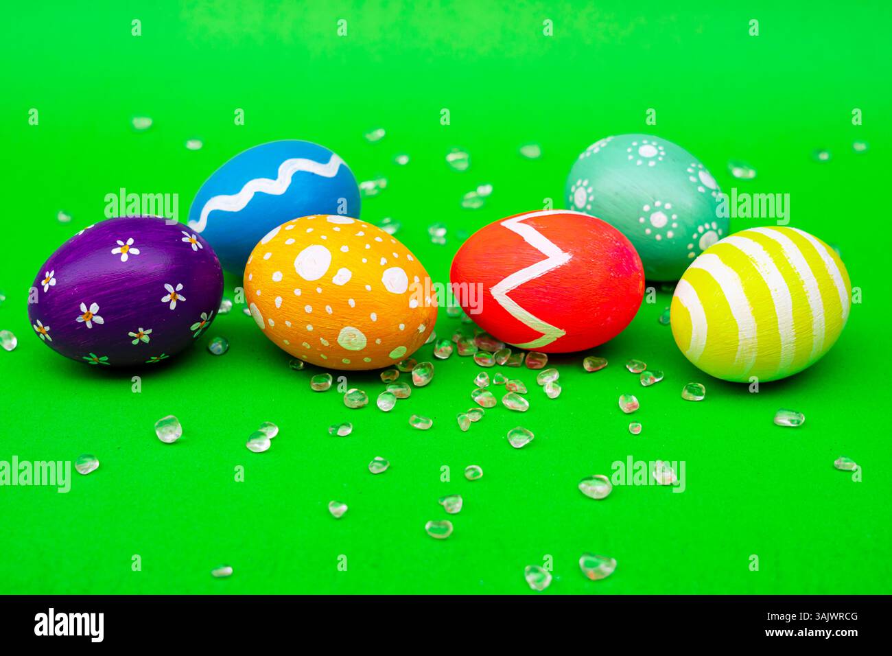 Oeufs de Pâques conçus colorés reposant sur un fond vert vibrant. Un groupe d'œufs de Pâques brillants peints à la main placés sur une surface verte propre, parfait Banque D'Images