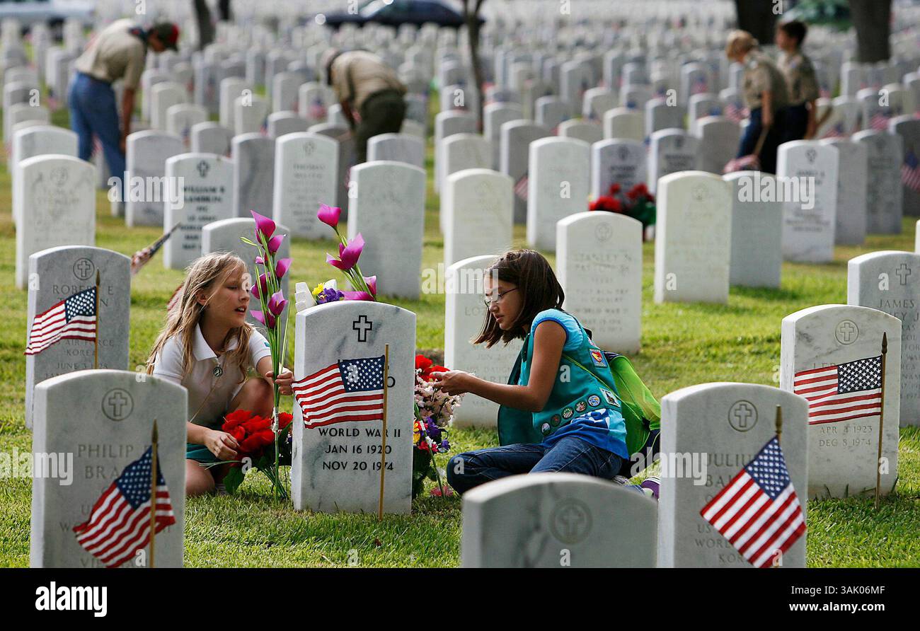 Les éclaireuses Katelyn Smith (à droite) et Lindsay Hearon de la troupe 725 à Castroville réarrangent des fleurs après avoir placé un drapeau américain sur une tombe tout en rejoignant des centaines d'autres éclaireuses pour l'événement de placement de drapeau au cimetière national de Fort Sam Houston le vendredi 22 mai 2009. Les éclaireurs ont traversé le cimetière pour mettre un drapeau sur chacune des 98 000 tombes. L'événement a eu lieu pour commémorer le Memorial Day. Kin Man hui/kmhui@express-news.net (image crédit : © San Antonio Express-News/ZUMA Press) Banque D'Images