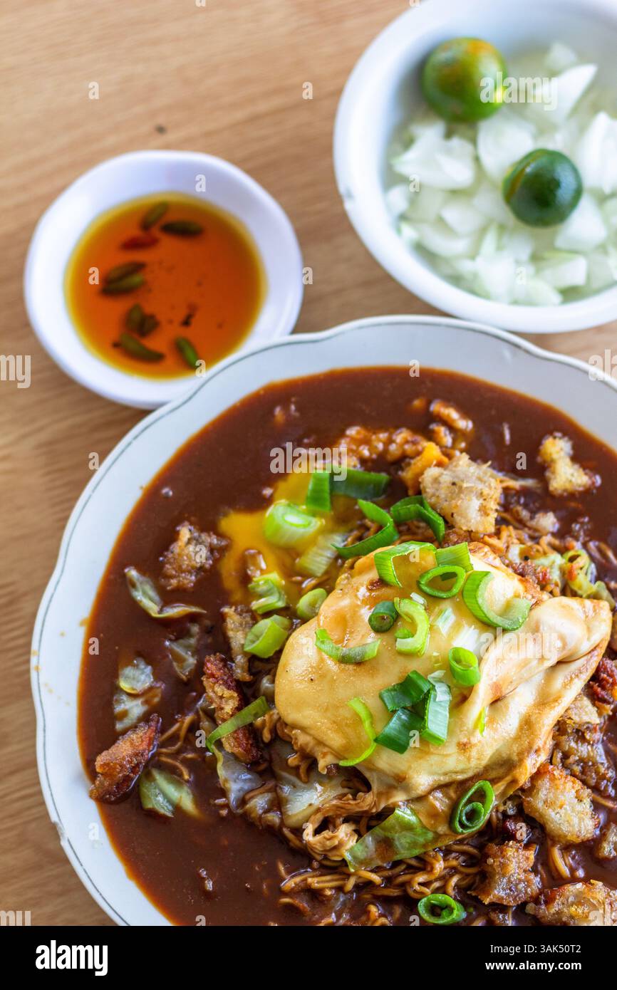 Une assiette de Pansit Cabagan, un plat traditionnel de nouilles d'Isabela, Philippines, servi avec des condiments assortis sur le côté Banque D'Images