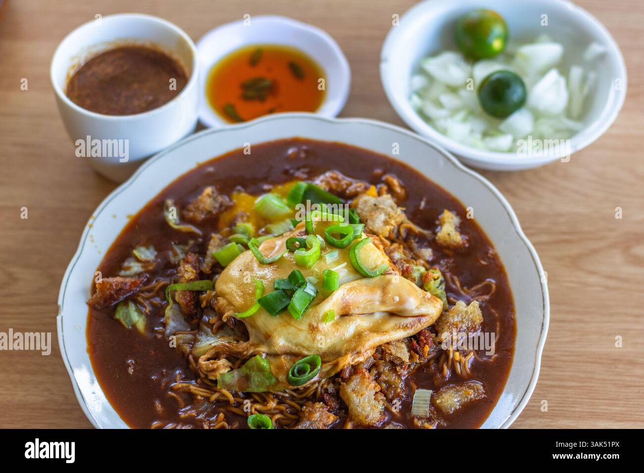 Une assiette de Pansit Cabagan, un plat traditionnel de nouilles d'Isabela, Philippines, servi avec des condiments assortis sur le côté Banque D'Images