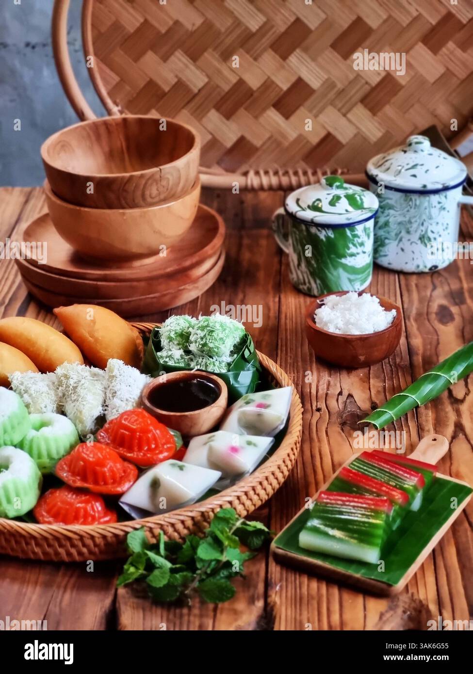 Des gâteaux indonésiens traditionnels colorés, également connus sous le nom de 'Kue basah', sont exposés sur une poêle en bambou tissé avec une couche de feuilles de bananier. Idéal pour culinaire Banque D'Images