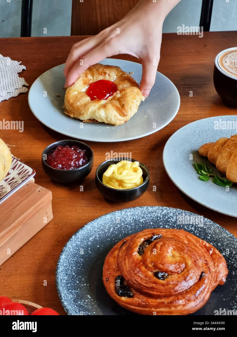 Plusieurs croissants fraîchement cuits sur une assiette en céramique, à côté d'une tasse de café, un petit pot de crème et de confiture. Cette image convient aux menus de café, foo Banque D'Images