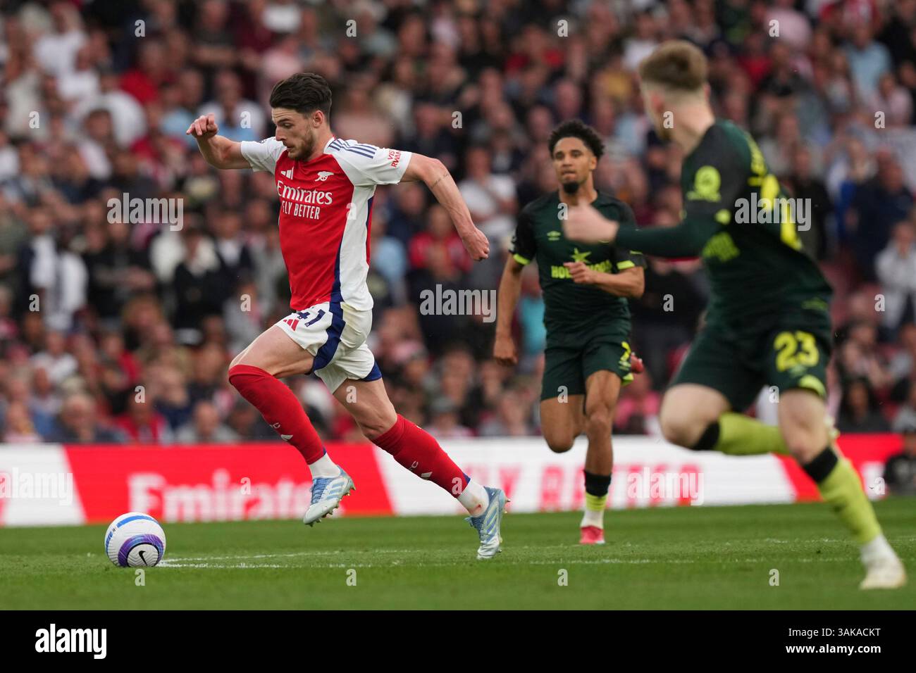Arsenal's Declan Rice, left, controls a ball chased by Brentford's Keane Lewis-Potter during the English Premier League soccer match between Arsenal and Brentford at Emirates Stadium in London, Saturday, April 12, 2025. (AP Photo/Frank Augstein) Banque D'Images