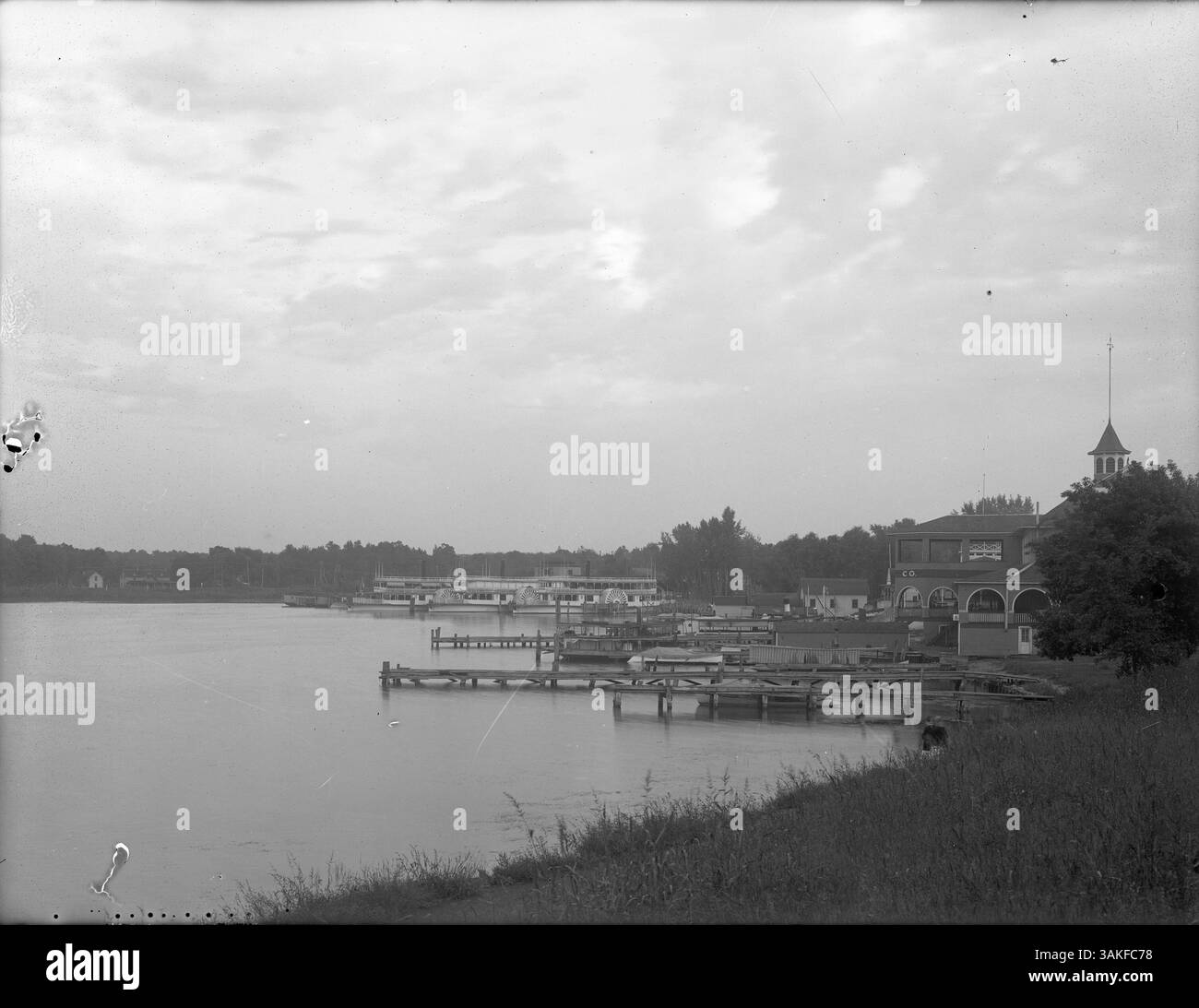 La scène au bord du lac à Excelsior, Minnesota, montre un terminal de ferry à l'extrême droite, avec des roues latérales et divers autres bateaux amarrés. La région reflète l'importance du transport et des loisirs sur les lacs. Banque D'Images