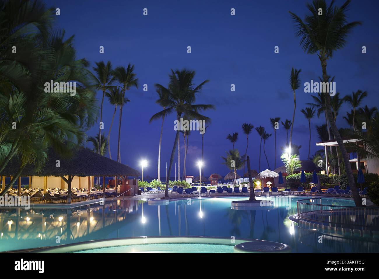 Tropical Resort dans la nuit. Voir avec le restaurant vide, énormes palmiers et des lumières électriques reflétant dans la piscine en premier plan Banque D'Images