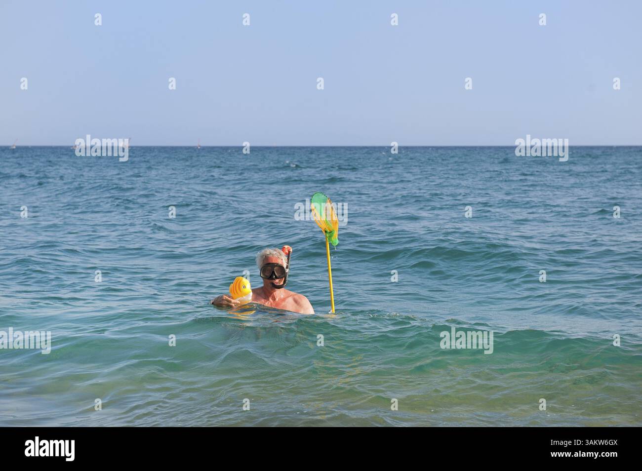L'homme attrape un poisson jouet dans la mer pendant la plongée avec tuba Banque D'Images