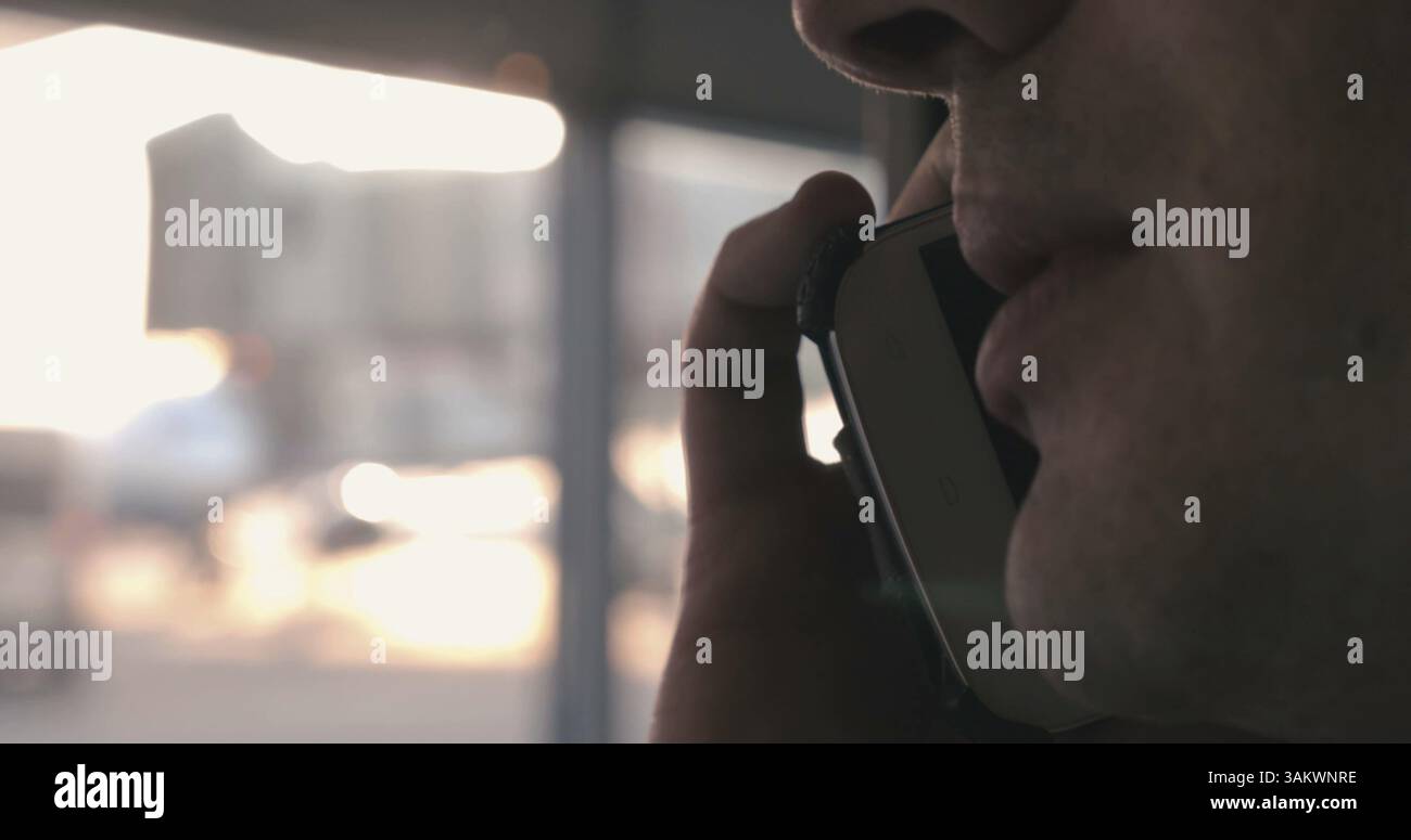 Gros plan d'un homme en conversation téléphonique à l'aéroport. Fenêtre floue en arrière-plan Banque D'Images