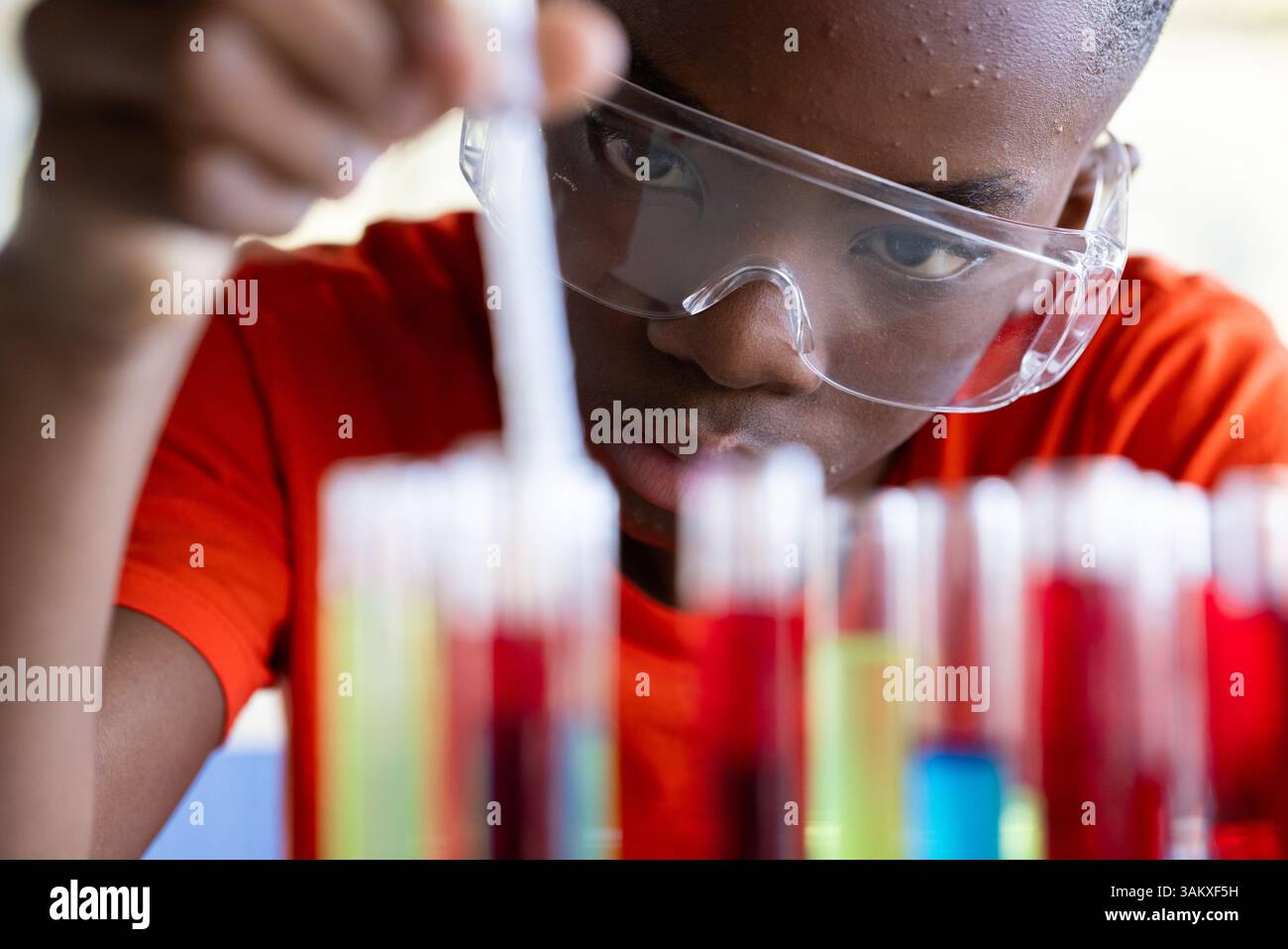 Mener une expérience scientifique, étudiant à l'école portant des lunettes de sécurité se concentrant sur les tubes à essai Banque D'Images