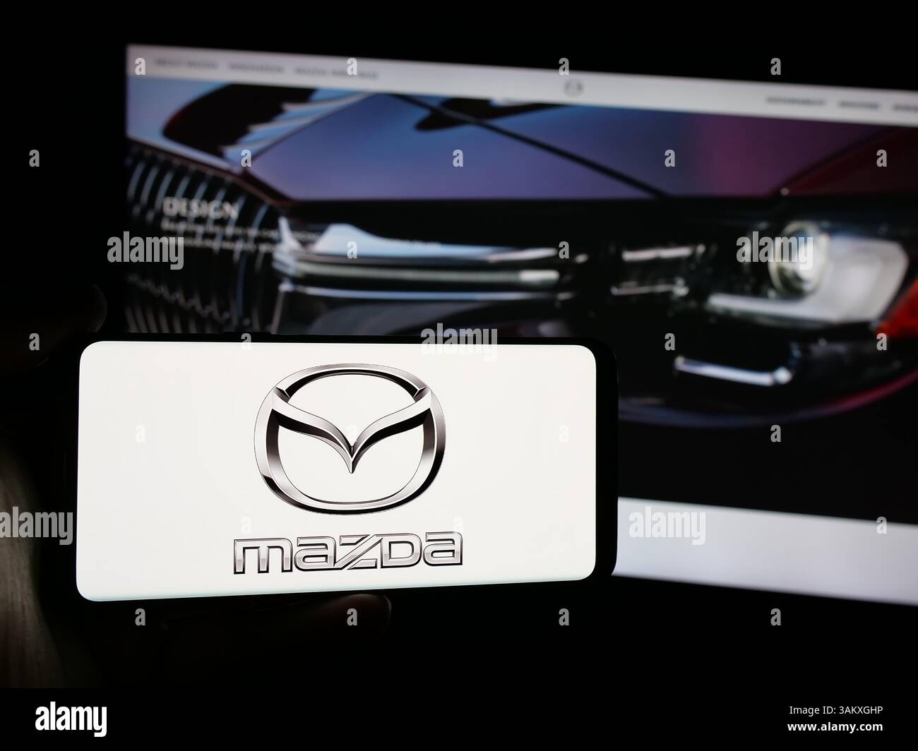 Stuttgart, Allemagne - 11-27-2024, personne tenant un smartphone avec le logo de la société automobile japonaise Mazda Motor Corporation sur l'écran Banque D'Images