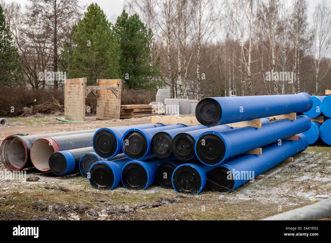 Tuyaux industriels bleus empilés sur des supports en bois sur un chantier de construction Banque D'Images