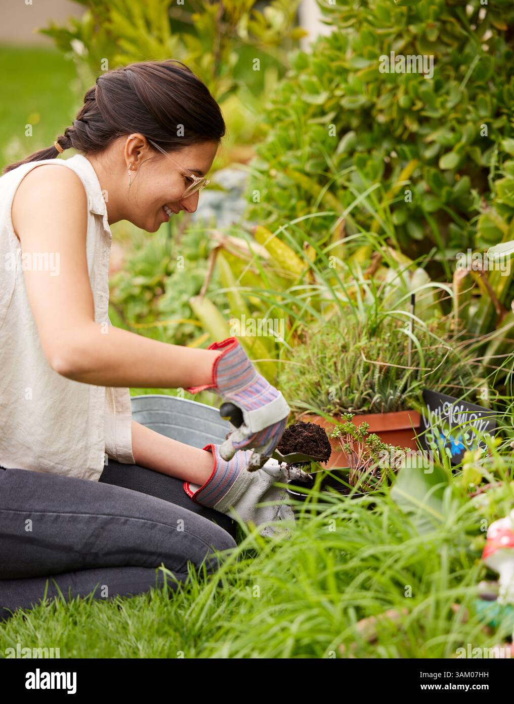 Jardinage, printemps et femme avec des fleurs dans la cour arrière pour l'environnement naturel, la croissance et l'écosystème. Nature, jardinier et personne plantant des graines, des arbres Banque D'Images