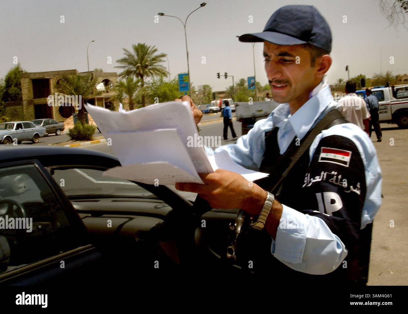 22 juin 2004 - Etats-Unis - KRT STAND ALONE WORLD NEWS PHOTO SLUGGED : USIRAQ KRT PHOTO PAR KHAMPHA BOUAPHANH/FORT WORTH STAR-TELEGRAM (DALLAS OUT) (22 juin) BAGDAD, IRAK -- un policier irakien passe en revue les documents d'un chauffeur sur son véhicule à un poste de contrôle à Bagdad, Irak, le mardi 22 juin 2004. Alors que la date du transfert du pouvoir approche, la police a intensifié ses efforts pour la sécurité. Récemment, ils ont reçu l'ordre de donner des citations pour des infractions au code de la route, une loi qui n'a pas été appliquée depuis le début de la guerre l'année dernière. (nk) 2004 (crédit image : © Khampha Bouaphanh/mct Banque D'Images