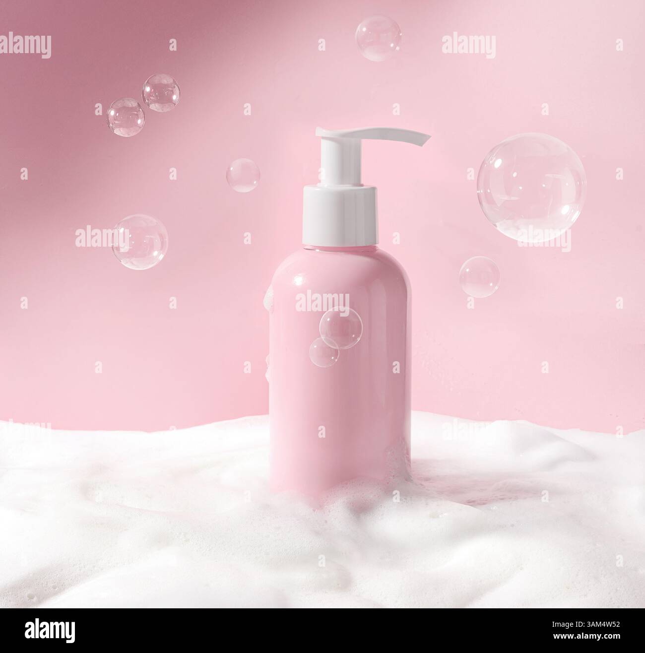 Un flacon à pompe rose élégant et chic entouré de mousse souple et de bulles de savon flottantes Banque D'Images