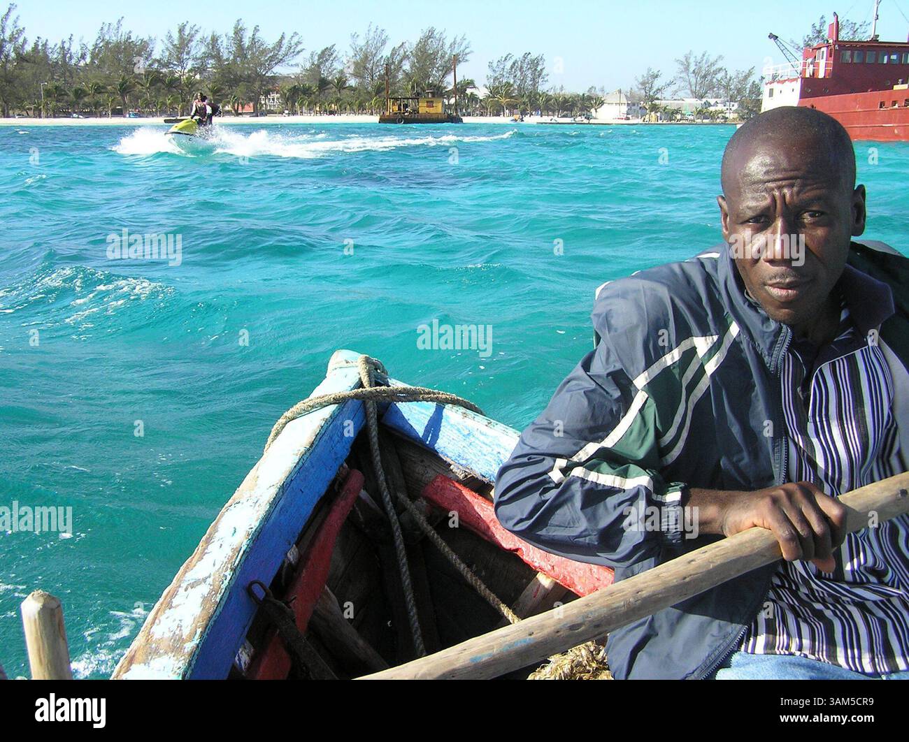 26 janvier 2005 - États-Unis - KRT WORLD NEWS STORY SLUGGED : HAITIANSLOOPS KRT PHOTOGRAPH BY JOE MOZINGO/MIAMI HERALD (SOUTH FLORIDA SUN-SENTINEL OUT) (janvier 30) NASSAU, BAHAMAS -- Flerison voit Louis Rows to the dock as a Jet ski whips by. Il a fallu cinq jours à Louis et à ses coéquipiers pour naviguer sur leur sloop, Betty Anne, d'Haïti, pour vendre du charbon de bois à Nassau, aux Bahamas. (cdm) 2005 (crédit image : © Joe Mozingo/mct/ZUMAPRESS.com) Banque D'Images