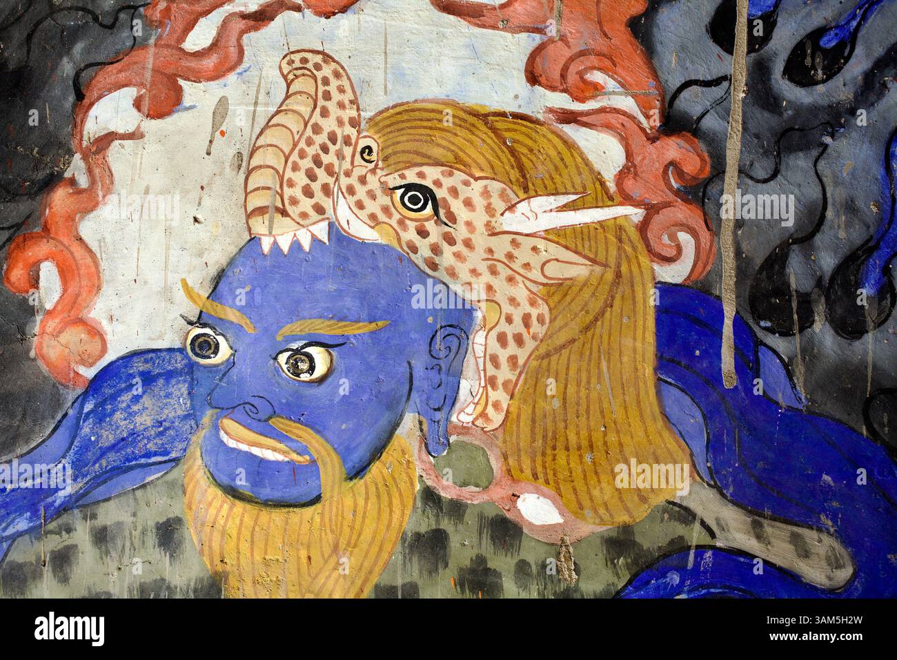 Gardien courageux au visage bleu avec coiffe féline et barbe dorée d'une murale de Vajrayāna, symbolisant l'assujettissement des instincts primaux. Banque D'Images