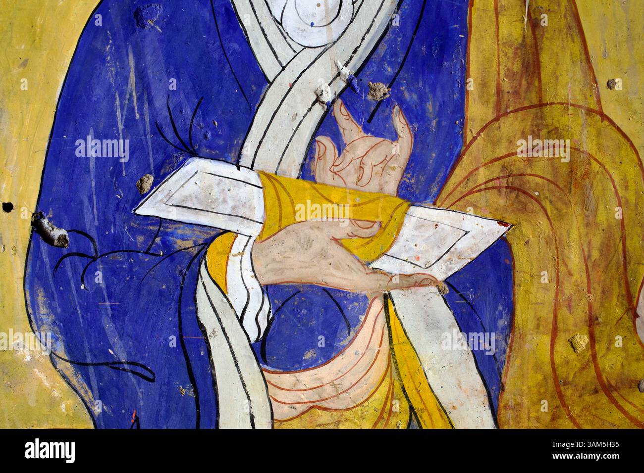 Détail des mains d’un moine tenant une écriture pecha et formant un mudra d’enseignement dans une murale du monastère Thiksey, Ladakh. Banque D'Images