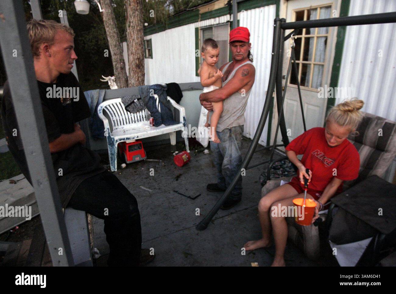 24 septembre 2005 - États-Unis - PAS DE MAGS, PAS DE VENTES -- KRT US NEWS STORY SLUGGED : WEA-RITA KRT PHOTO PAR MICHAEL AINSWORTH/DALLAS MORNING NEWS (24 septembre) LIBERTY, TX -- David Hilton, au centre, se tient avec les membres de la famille Kevin Edmonds, à gauche, Ryan Welch, 2 ans, et Kelly Welch sur le porche de sa maison mobile endommagée PAR l'ouragan Rita à Liberty, Texas, le samedi 24 septembre 2005. Lui et d'autres résidents de la région de basse altitude sont en danger parce que les eaux de crue de la rivière Trinity devraient augmenter en raison d'un rejet d'eau du lac Livingston. (MvW) 2005 (crédit image : © Michael Ainsworth/mct Banque D'Images