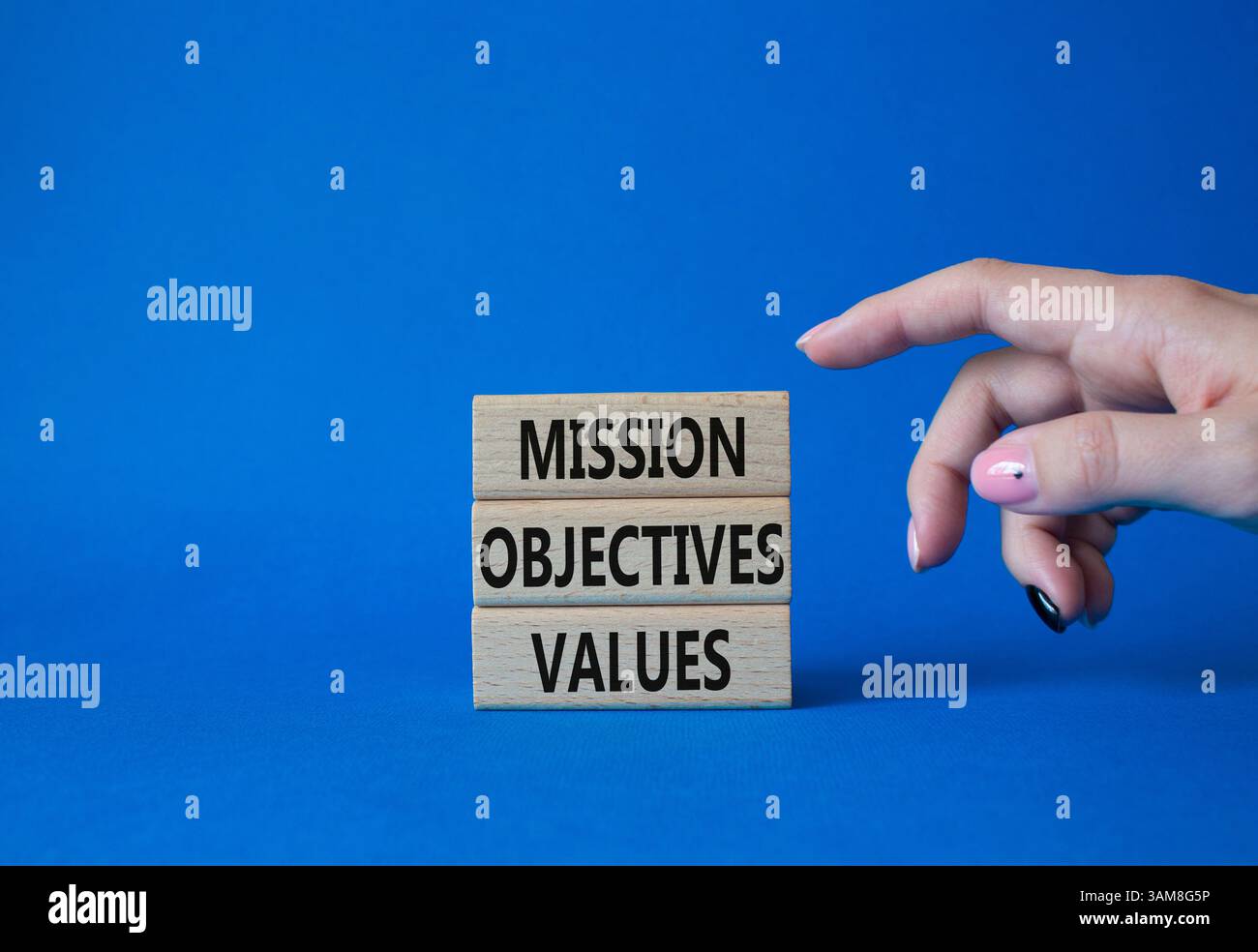 Symbole des valeurs des objectifs de mission. Mots conceptuels objectifs de mission valeurs sur blocs de bois. Beau fond bleu. Main d'homme d'affaires. Entreprise et Banque D'Images