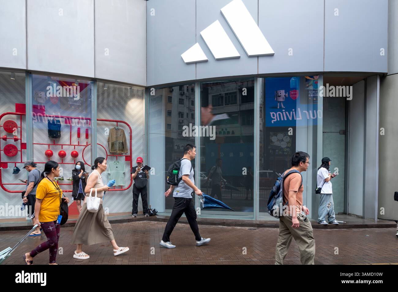 Des piétons marchent devant le magasin Adidas de la marque multinationale allemande de vêtements de sport à Hong Kong. Banque D'Images