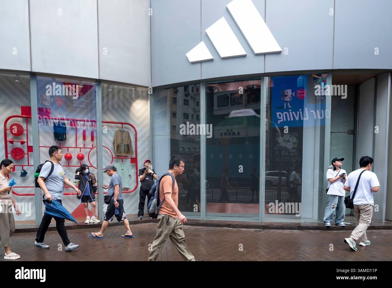Des piétons marchent devant le magasin Adidas de la marque multinationale allemande de vêtements de sport à Hong Kong. Banque D'Images
