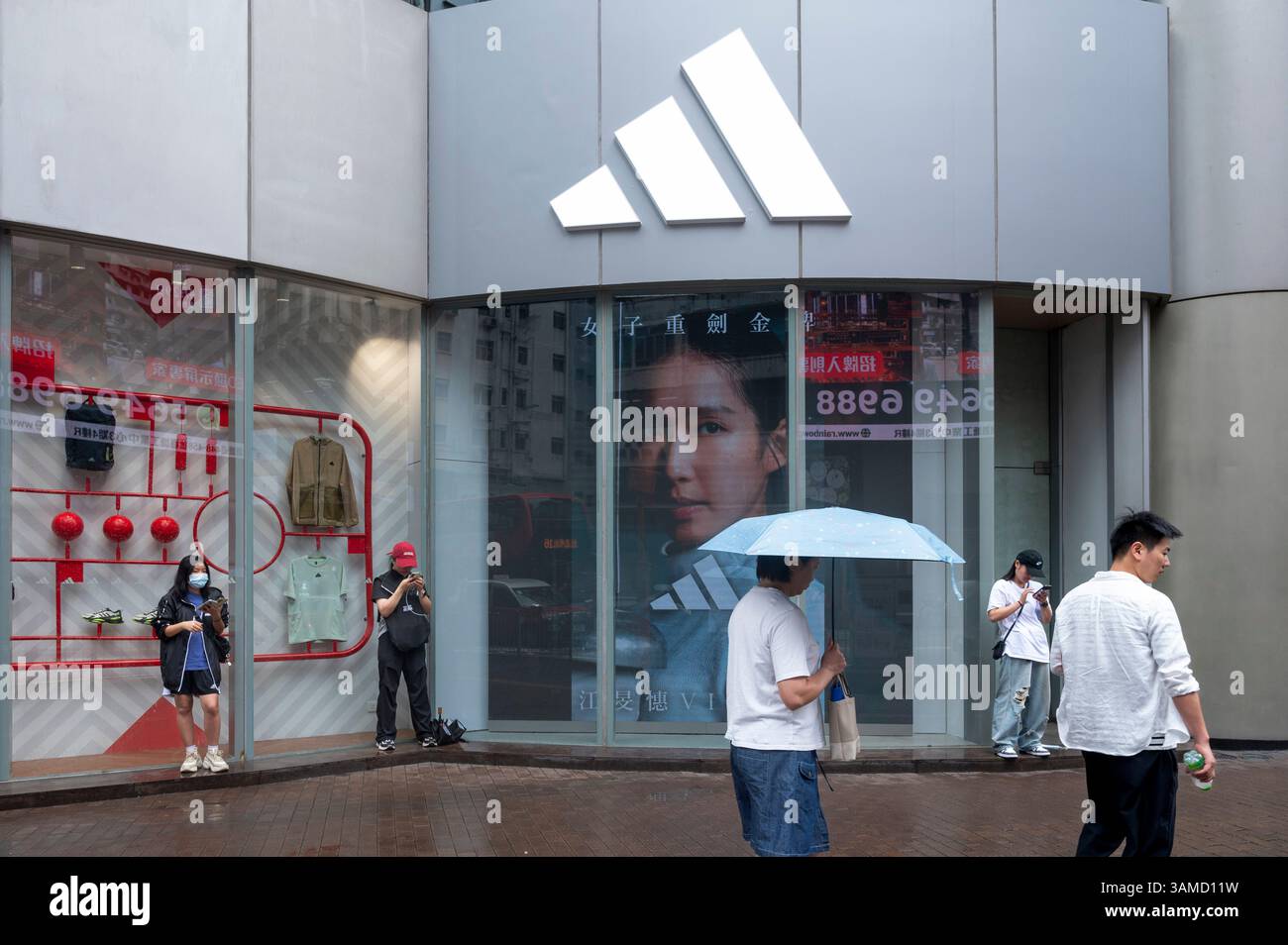 Des piétons marchent devant le magasin Adidas de la marque multinationale allemande de vêtements de sport à Hong Kong. Banque D'Images