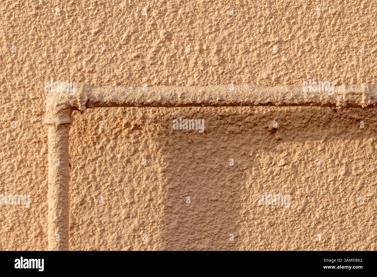 Une composition abstraite mettant en valeur la texture complexe d'un mur beige avec un tuyau. L'image met en évidence la texture et la structure du matériau, idéal pour b Banque D'Images