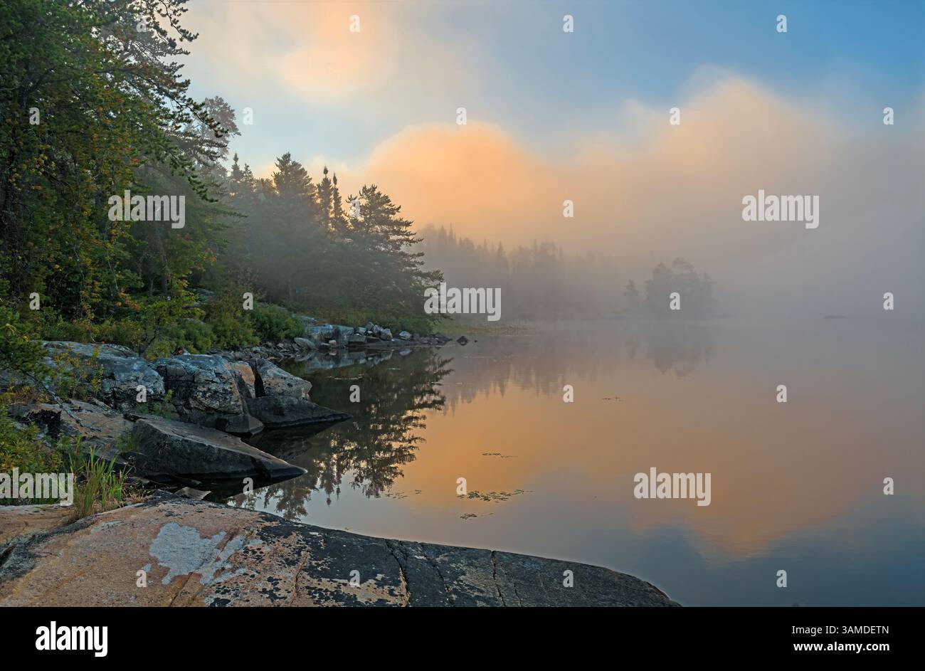 Nuages orange sur un matin de Foggy sur le lac Saganaga dans les eaux limitrophes du Minnesota Banque D'Images