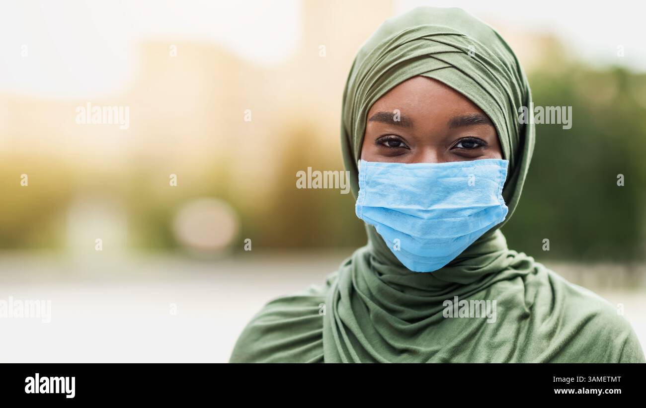 Bonne femme musulmane africaine en hijab portant un masque facial protecteur à l'extérieur Banque D'Images