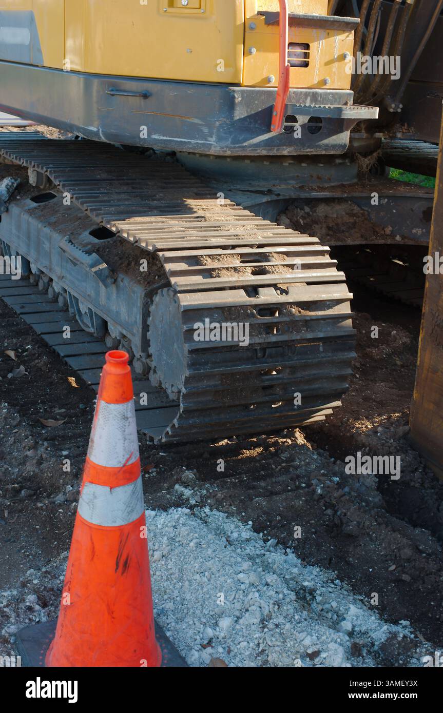 Équipement de construction lourd sur un chantier avec cônes de circulation. Gros plan d'une machine à chenilles extra-robuste sur un chantier de construction, avec des cônes de circulation à l'intérieur Banque D'Images