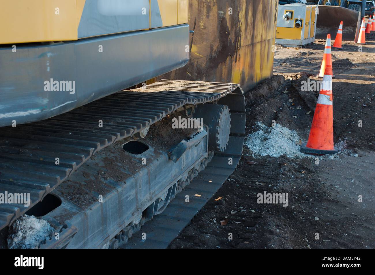 Équipement de construction lourd sur un chantier avec cônes de circulation. Gros plan d'une machine à chenilles extra-robuste sur un chantier de construction, avec des cônes de circulation à l'intérieur Banque D'Images