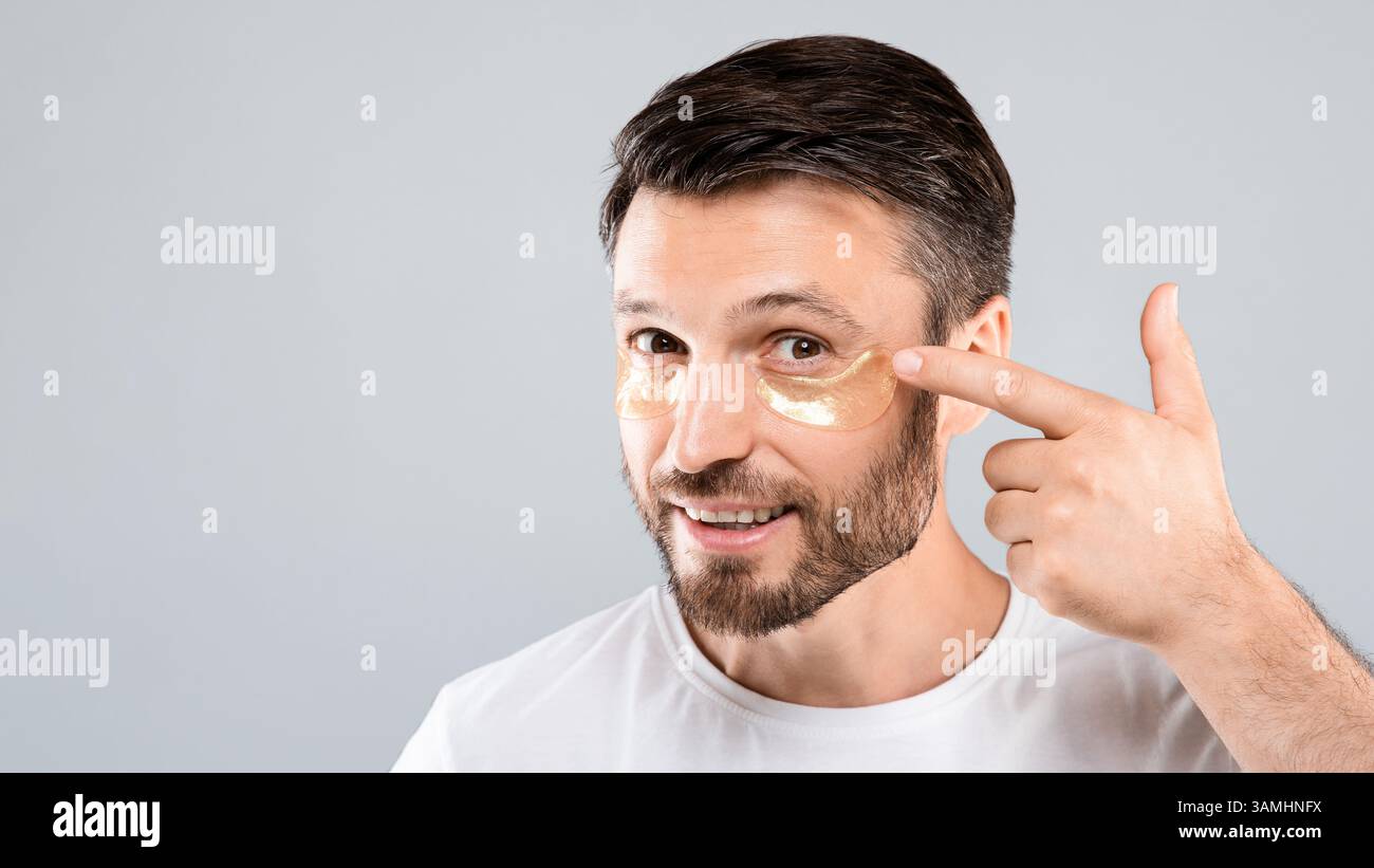 Beau homme appliquant des cellules oculaires sur son visage Banque D'Images