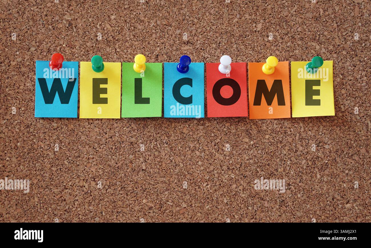 Mot de bienvenue et signe sur des notes de papier coloré épinglées avec des punaises multicolores sur un fond de concept accueillant de tableau d'affichage en liège. Banque D'Images