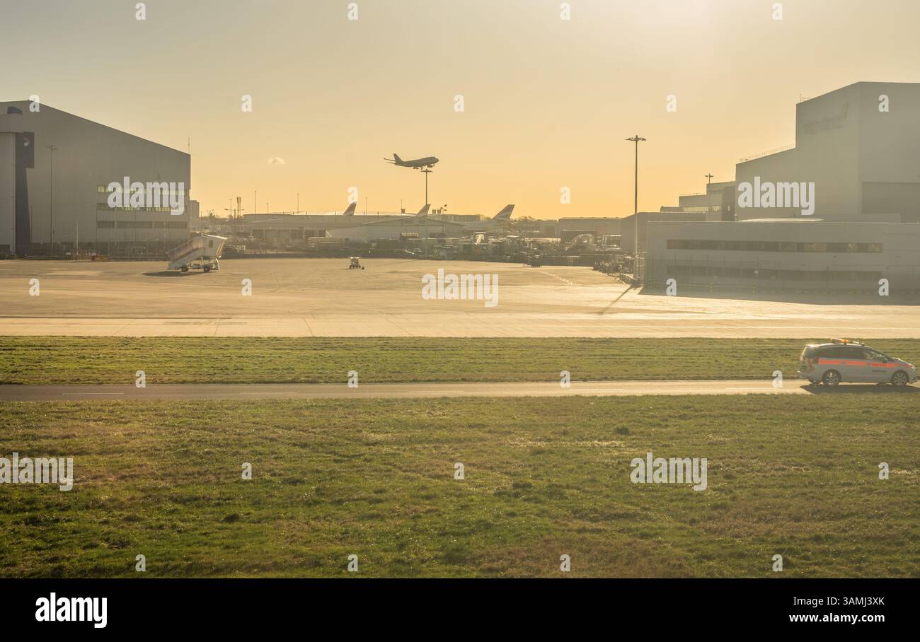 Heathrow, Londres - 28 janvier 2019 : lever de soleil à l'aéroport de Heathrow avec un avion volant en arrière-plan, Londres, Royaume-Uni Banque D'Images