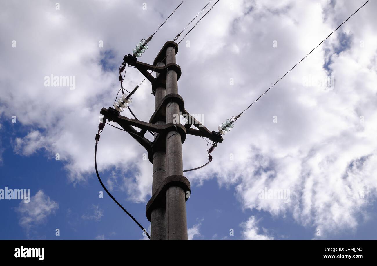 Poteau utilitaire en béton avec isolants verts sous un ciel nuageux Banque D'Images