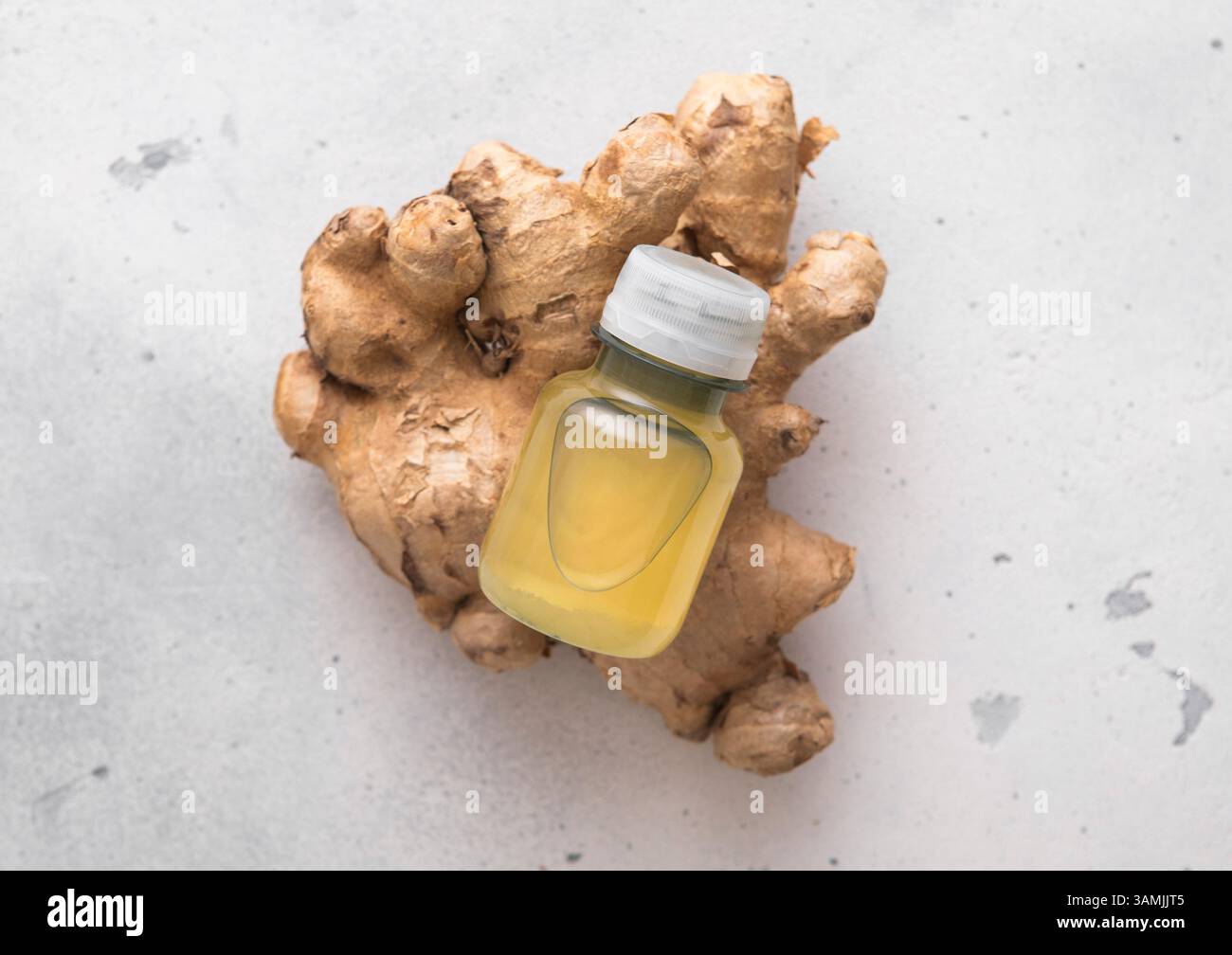 Bouteille de boisson énergétique de gingembre immunitaire sur le dessus de racine de gingembre cru frais à fond clair. Banque D'Images