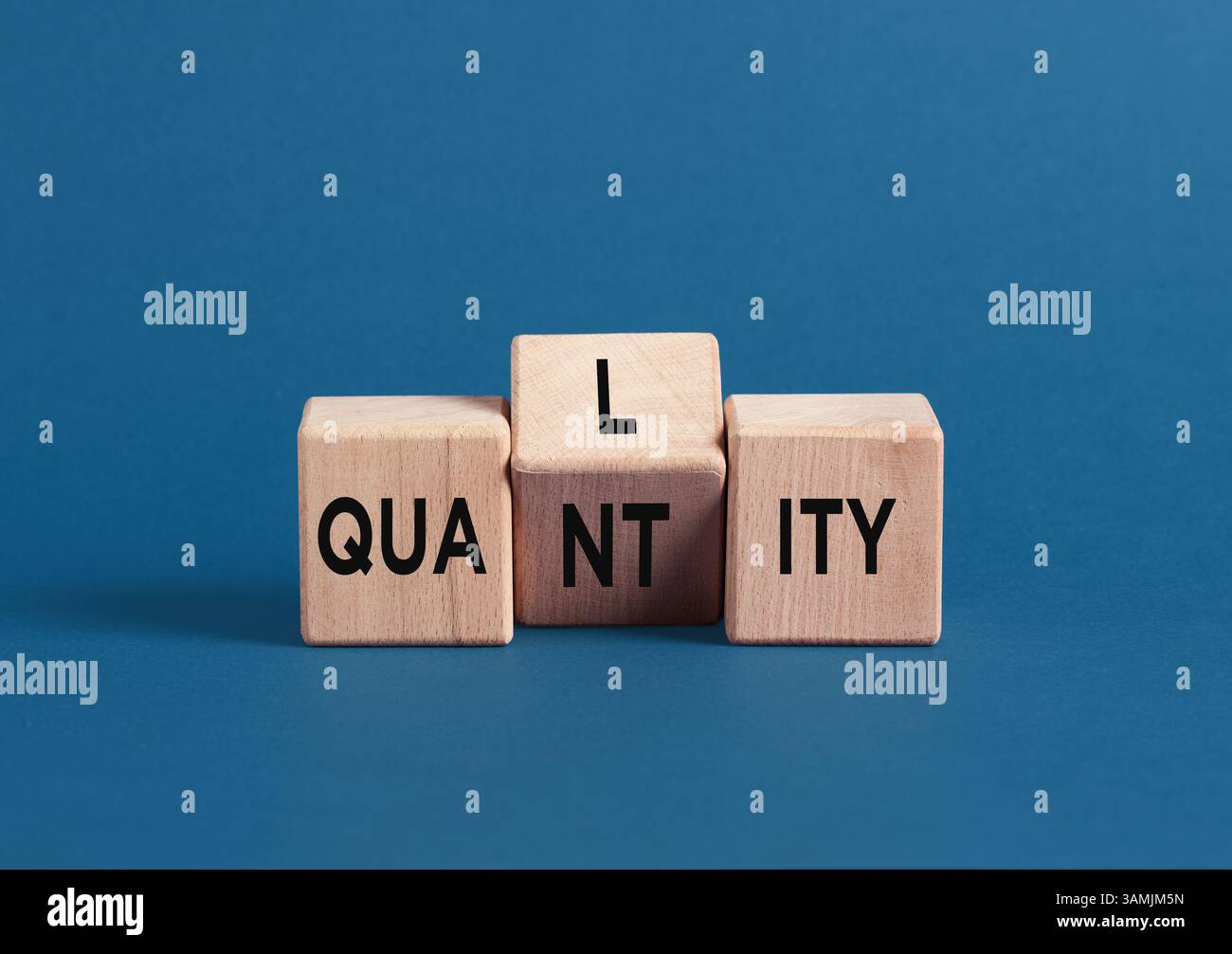 Les cubes en bois sur fond bleu avec les mots qualité et quantité symbolisent le concept de qualité sur quantité. Banque D'Images