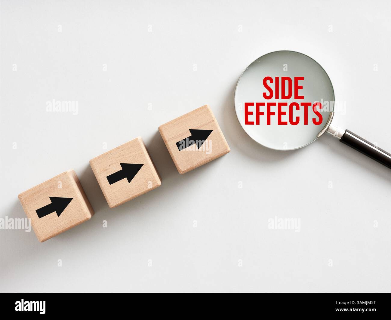 Loupe montrant des effets secondaires et des cubes en bois avec des flèches pointant vers elle, sur un fond blanc Banque D'Images